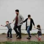A joyful family walking together outdoors, holding hands in a playful and happy moment.