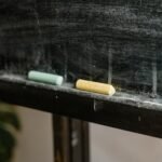 Detailed shot of colored chalk pieces on a dusty blackboard ledge.